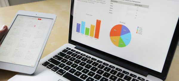 Laptop displaying charts and graphs with tablet calendar for data analysis and planning.