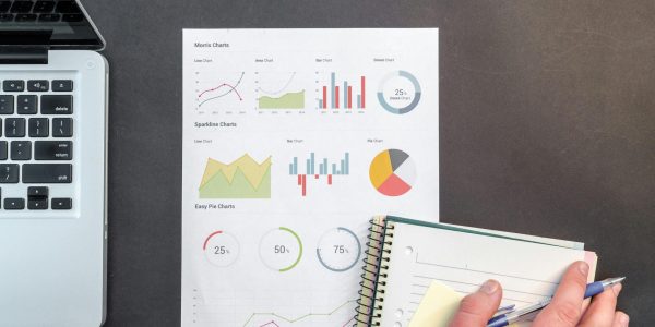 Overhead view of a business desk with charts and a laptop, ideal for data analysis concepts.